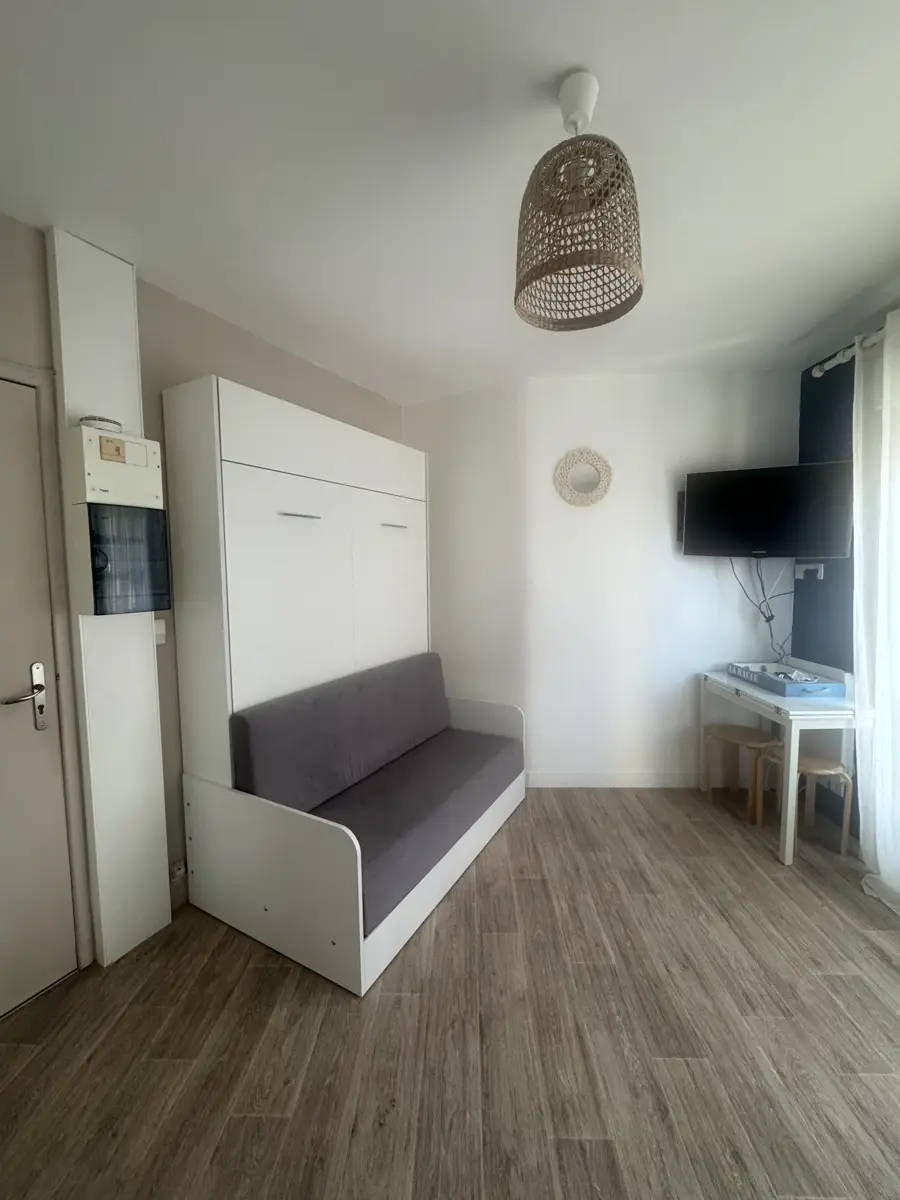 Das Wandbett als Sofa eingeklappt, mit Schreibecke und Fernseher
